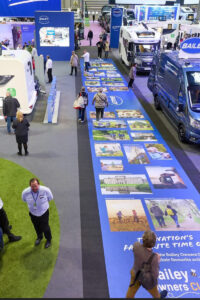 A large indoor exhibition features numerous recreational vehicles