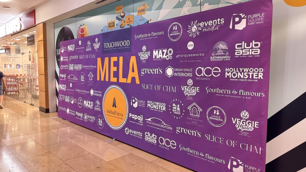 Large purple banner advertising a 'MELA' event with various sponsor logos