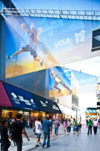 Shoppers walking past large Visa Olympic banners at Westfield Stratford City