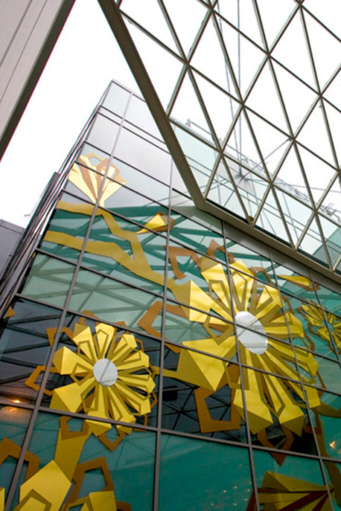 glass facade of a modern building adorned with large, abstract yellow and white vindow vinyl decals