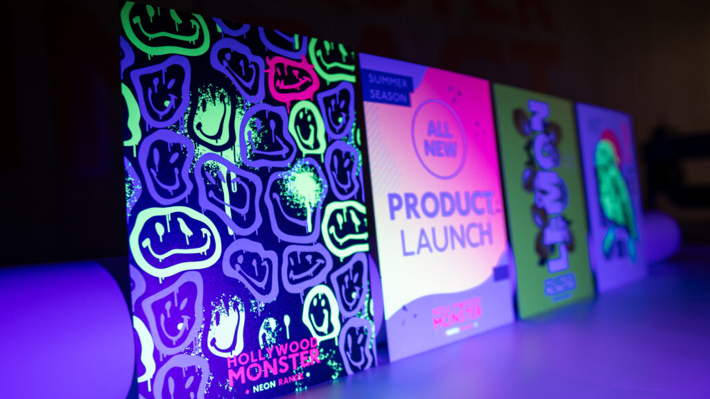 Neon product launch flyers for the "Hollywood Monster" brand, featuring melting smiley faces and "LEMON" designs, glowing under blacklight.