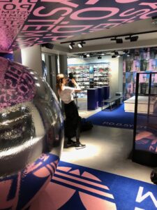 Woman taking a photo in an Adidas store which has been fitted with campaign rollout branding.