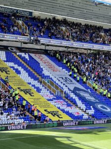 Crowd segregation banners in a football stadium stand.