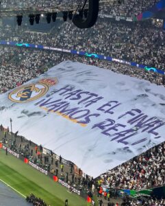 Large tifo banner with the Real Madrid crest and "Hasta El Final ¡Vamos Real!" covering a stadium section.