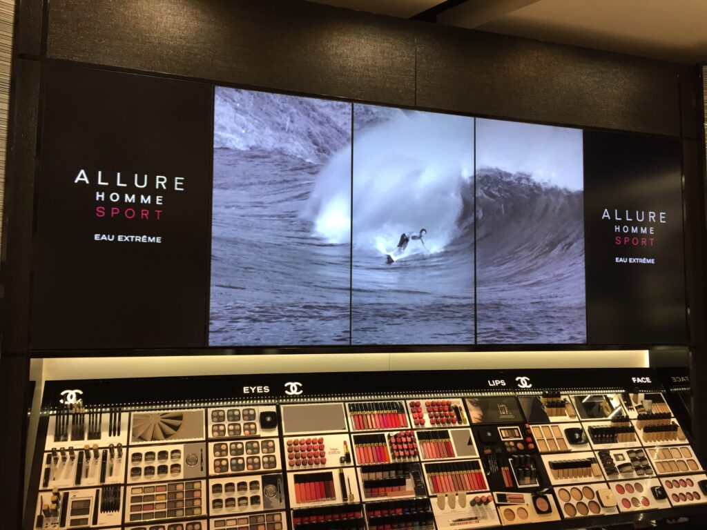 The image shows a large, high-end display for the Chanel Allure Homme Sport fragrance in what appears to be a retail store or a mall.
