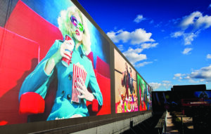 Large advertising hoarding at Westfield Stratford featuring a woman holding popcorn and a drink in a cinema seat.