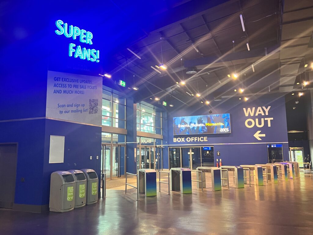 BP Pulse entrance with an integrated digital sign service, a neon super fans sign and digital poster next to way out wayfinding