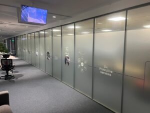 Bespoke window graphics featuring frosted privacy film and custom-etched branding on glass office partitions.
