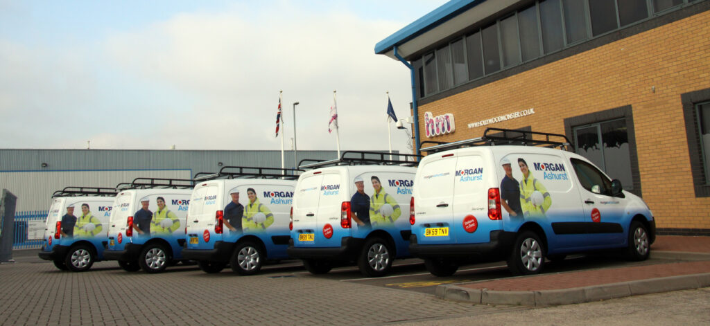 Five vans with morgan ashurst promotional branding parked outside hollywood monsters hq