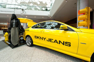 A vehicle wrap on a yellow car with DKNY jeans on the side in black font